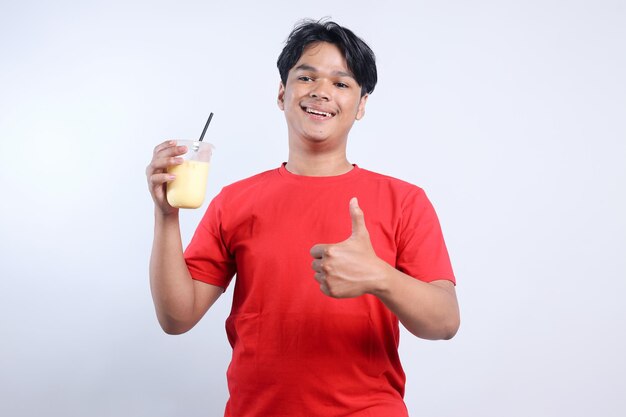 Młody Azjat pije zdrowy smoothie jabłkowy z szczęśliwą twarzą i robi ok znak kciuk w górę z płetwą