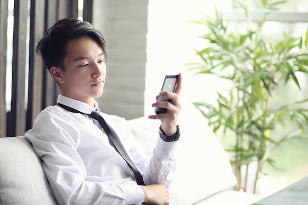 Młody azjatycki biznesmen czeka na partnera w kawiarni Spotkanie biznesowe w restauracji Koreański młody mężczyzna rozmawia przez telefon w kawiarni