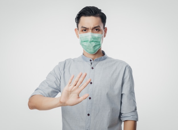 Młody Azjatycki biznesmen jest ubranym higieniczną maskę gestykuluje przerwę zapobiegać infekcję