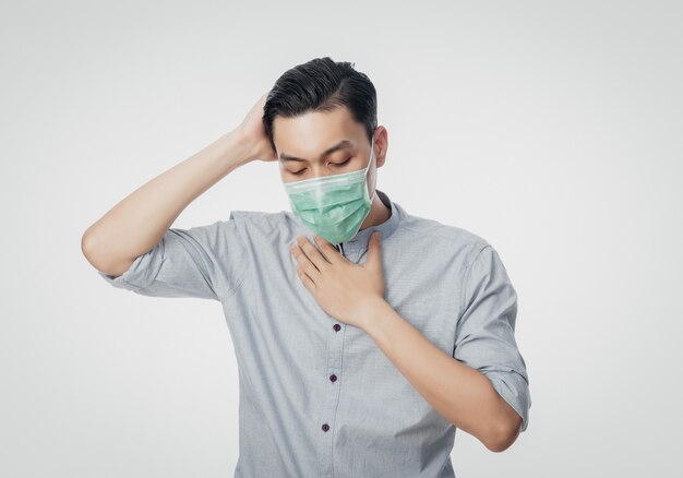 Młody azjatycki biznesmen w higienicznej masce z bólem gardła i grypą, 2019-nCoV lub koronawirusem.