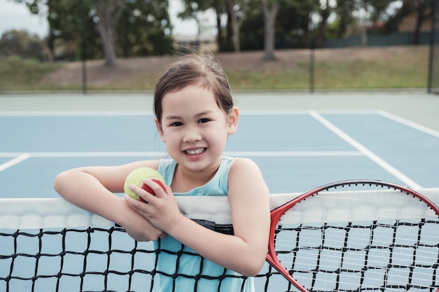 Młody Azjatycki dziewczyny gracz w tenisa na plenerowym błękita sądzie