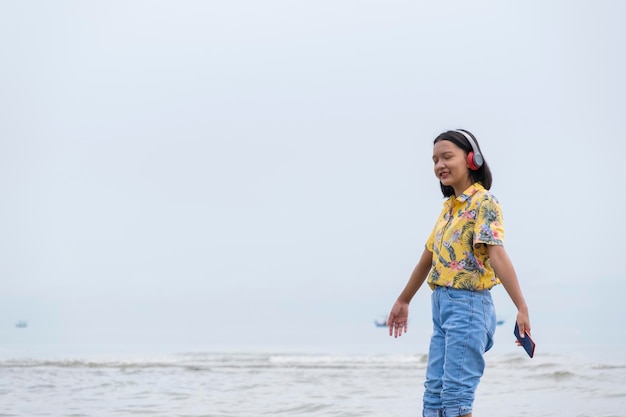 Młody azjatycki giel słucha muzyki nad pięknym morzem