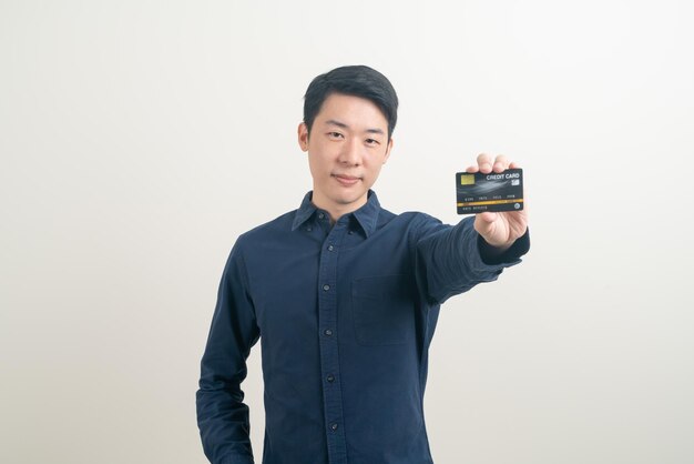Młody Azjatycki mężczyzna trzyma kredytową kartę