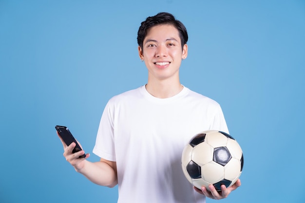 Młody azjatycki mężczyzna trzyma piłkę na tle