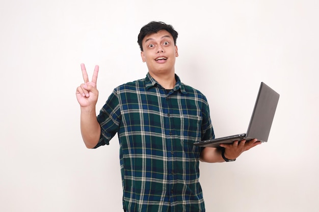 Młody azjatycki student pokazujący dwa palce, trzymając laptop