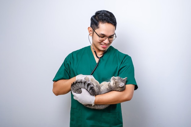 Zdjęcie młody azjatycki weterynarz w zaroślach i okularach bada kota domowego