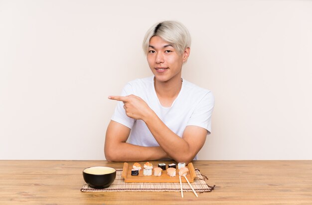 Młody azjatykci mężczyzna z suszi w stołowym wskazuje palcu strona