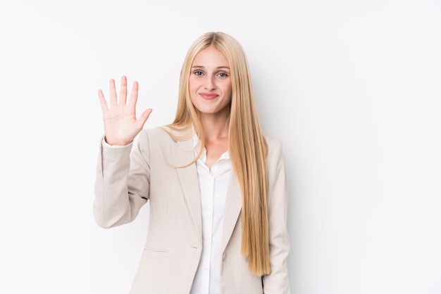 Młody biznes blond kobieta na białej ścianie uśmiechnięty wesoły pokazując numer pięć palcami.