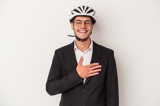 Młody biznes kaukaski mężczyzna trzyma kask rowerowy na białym tle śmieje się głośno trzymając rękę na klatce piersiowej.