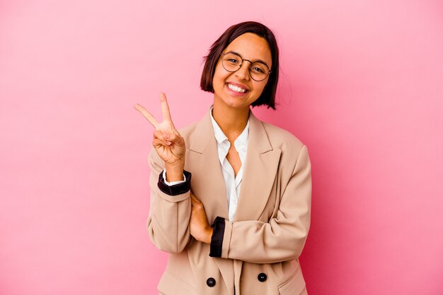 Młody biznes kobieta rasy mieszanej na białym tle na różowej ścianie pokazuje numer dwa palcami.
