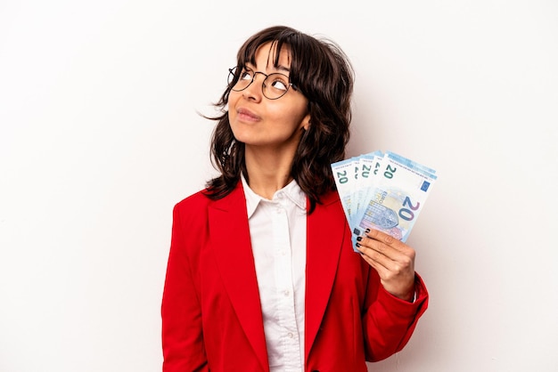Młody biznes latynoska kobieta trzyma banknoty na białym tle marząc o osiągnięciu celów i celów