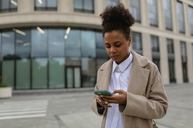 Młody biznesmen african american kobieta pisania na telefonie komórkowym na tle biznesu