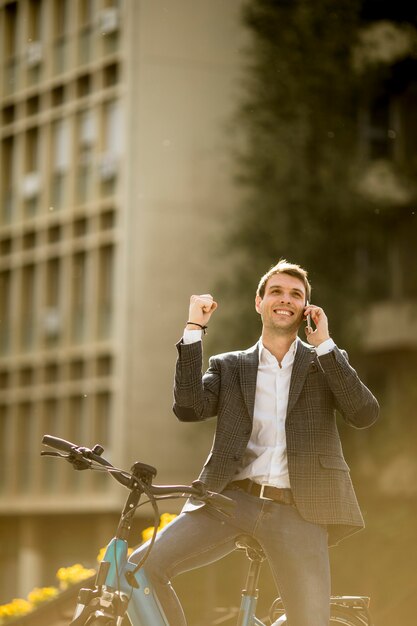 Młody biznesmen na ebike używać telefon komórkowego