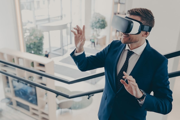 Młody biznesmen noszący gogle wirtualnej rzeczywistości pracujący w biurze