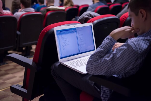 młody biznesmen piszący na klawiaturze laptopa podczas seminarium w sali konferencyjnej