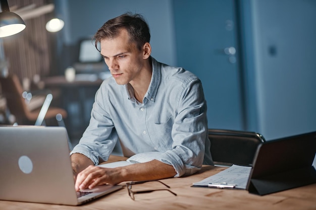 Młody biznesmen pracuje późno w nocy na laptopie w biurze