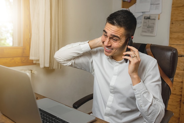 Młody Biznesmen Rozmawia Przez Telefon I Czuje Się Winny, Zmartwiony Problemem W Pracy, Położył Rękę Za Głową.