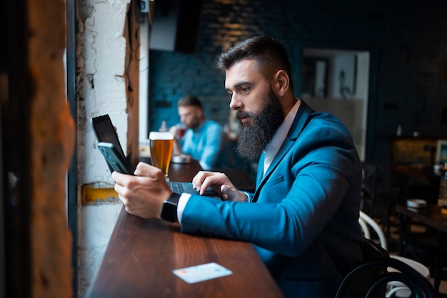 Młody biznesmen używający swojego smartfona w barze