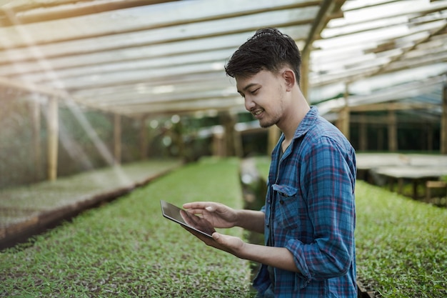 Zdjęcie młody biznesmen za pomocą tabletu sprawdzającego koncepcję fotografii cyfrowej i inteligentnej farmy