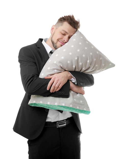 Młody biznesowy mężczyzna ściska poduszkę i kontynuuje spanie odizolowywający na bielu