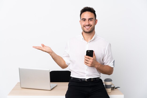Młody biznesowy mężczyzna z telefonem komórkowym w miejscu pracy trzyma copyspace imaginacyjnego na palmie