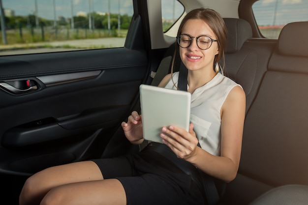 Młody bizneswoman z gadżetu smartphone obsiadaniem w nowożytnym samochodzie