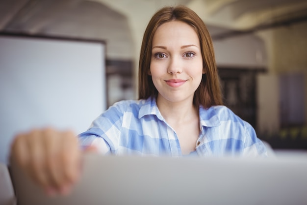 Zdjęcie młody bizneswomanu mienia laptop przy biurkiem w kreatywnie biurze