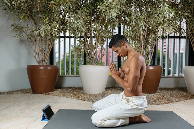 Młody Brazylijczyk przygotowuje się do rozpoczęcia zajęć jogi online. Powitanie.