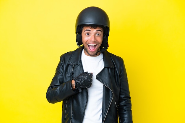 Młody Brazylijczyk z kaskiem motocyklowym na białym tle na żółtym tle z niespodzianką wyrazem twarzy