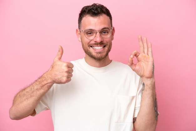 Młody Brazylijski Mężczyzna Na Białym Tle Na Różowym Tle W Okularach I Robi Znak Ok