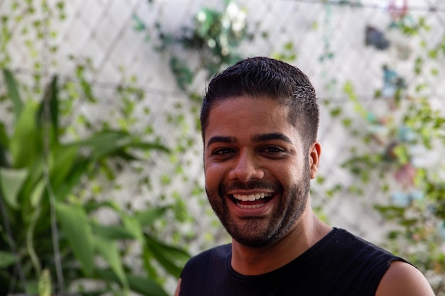 Młody brazylijski mężczyzna uśmiechający się do kamery w swoim domowym ogrodzie