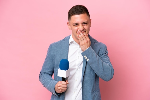 Młody brazylijski prezenter mężczyzna na białym tle na różowym tle szczęśliwy i uśmiechnięty zakrywający usta dłonią