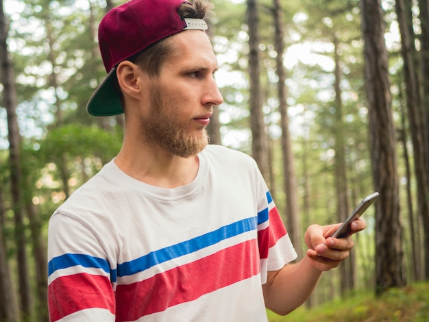 Młody brodaty blogger hipster robi na żywo w sieci społecznościowej chodzenie po lesie
