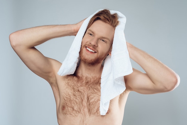 Młody brodaty mężczyzna wyciera mokre włosy ręcznikiem