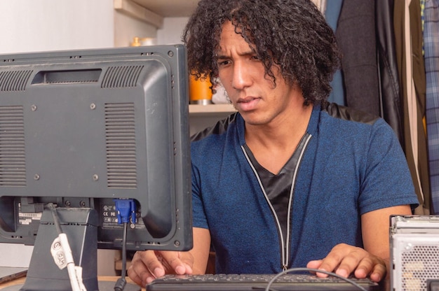 Młody brunetka mężczyzna w pomieszczeniu pracujący na komputerze