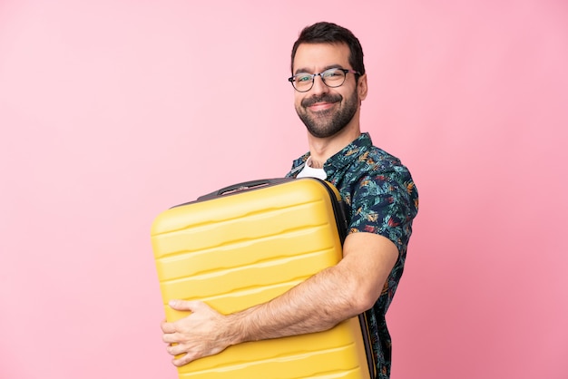 Młody caucasian mężczyzna nad odosobnioną ścianą w wakacje z podróży walizką