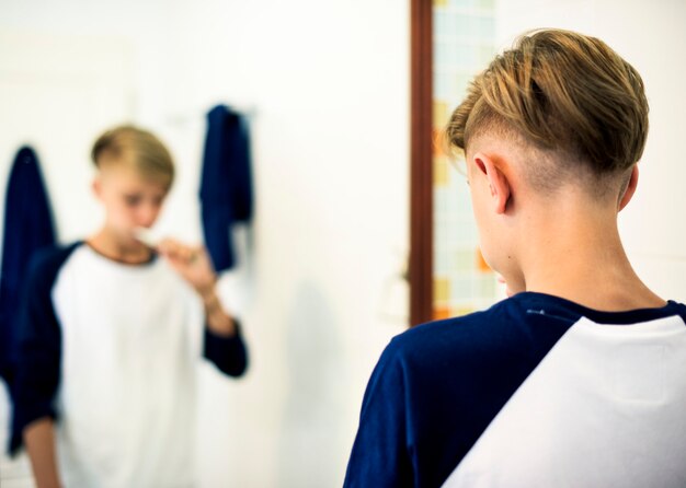 Młody caucasian mężczyzna szczotkuje zęby w łazience