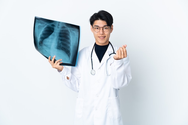 Młody chiński lekarz mężczyzna posiadający radiografię na białym tle na białej ścianie, dzięki czemu pieniądze gest