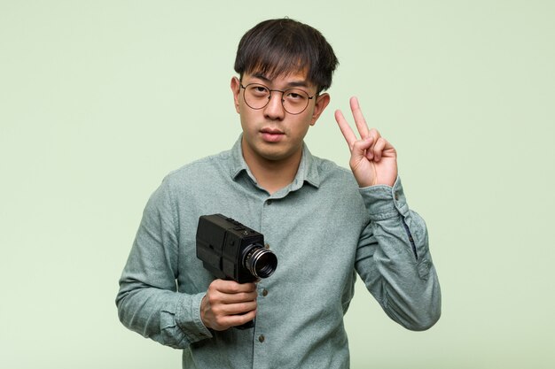 Młody Chiński Mężczyzna Trzyma Rocznik Kamerę Pokazuje Numer Dwa