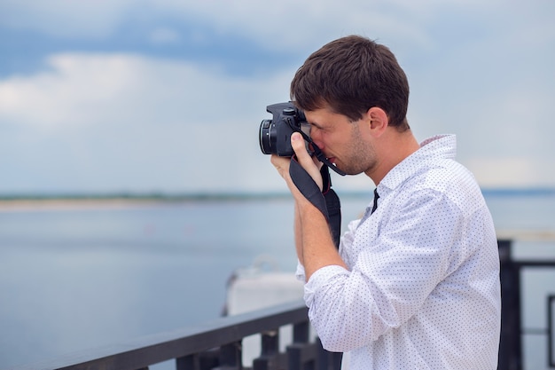 Młody chłopak fotografuje rzekę od nasypu w aparacie