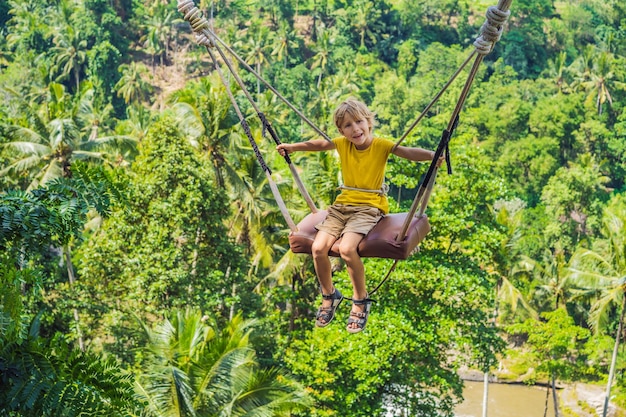 Młody chłopak huśta się w dżungli na wyspie Bali Indonezja Huśtawka w tropikach Trend huśtawki na Bali Podróżowanie z dziećmi koncepcja Co robić z dziećmi Miejsce przyjazne dzieciom