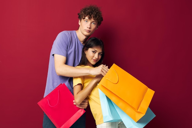Młody chłopak i dziewczyna kolorowe torby na zakupy zabawa na czerwonym tle niezmienione