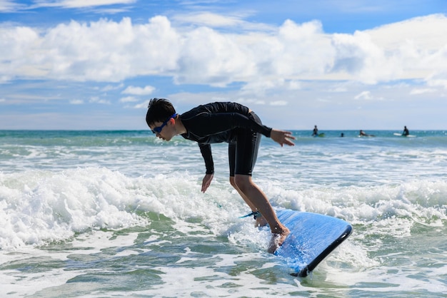 Zdjęcie młody chłopak, nowy uczeń surfingu, traci równowagę ciała i spada z deski surfingowej do wody podczas zajęć