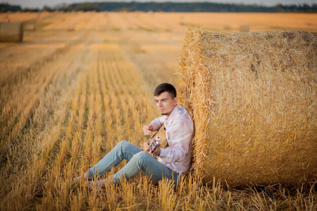 Młody chłopak relaks na wsi podczas gry na gitarze