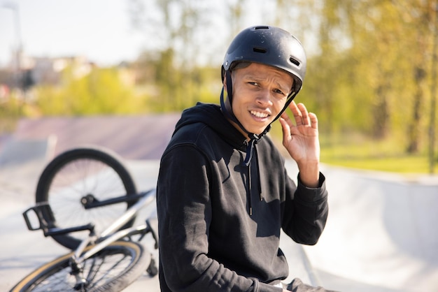 Młody Chłopak Siedzi Na Rampie W Skateparku Z Rowerem Leżącym Za Nim