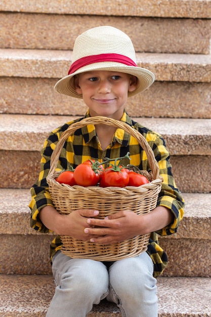 Młody chłopak trzymający zbiory organicznych pomidorów