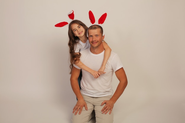młody chłopak w koszulce przytula córkę w białej koszulce z uszami królika na głowie