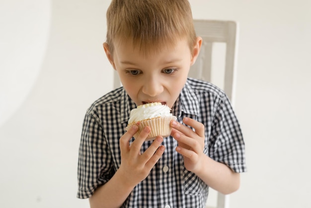 Młody chłopak w koszuli je tort na jasnym tle Radość jedzenia słodyczy