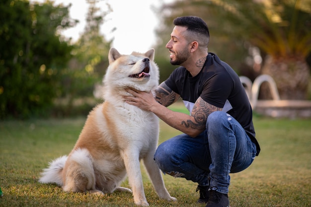 Młody chłopak z tatuażami szczęśliwy, uśmiechając się z psem