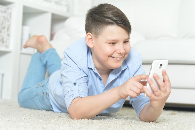 Młody chłopak ze smartfonem grający w grę w domu